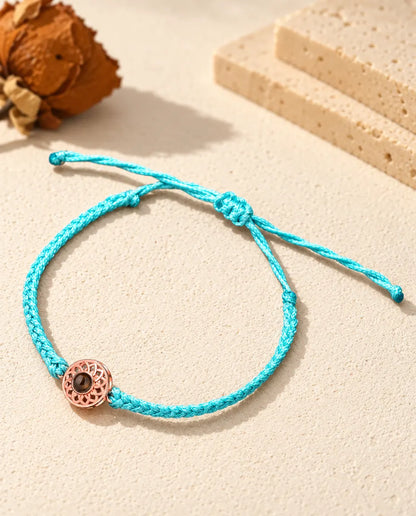 Círculo color oro rosa en un cordón trenzado fino azul con nudo corredizo ajustable