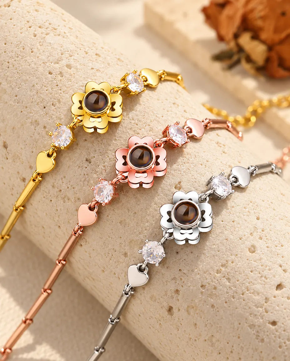 Tres pulseras de trébol en dorado, color oro rosa y plateado sobre un bloque de travertino