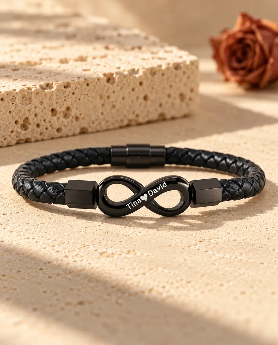 Pulsera infinito personalizada para hombre en negro, con cordón de cuero sintético trenzado y dos nombres grabados con un corazón