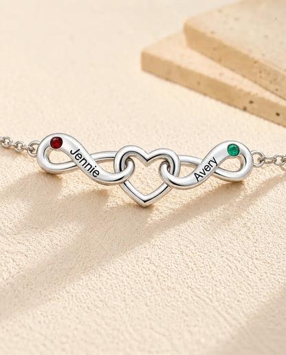 Pulsera Infinito Personalizada 2 Nombres - dos lazos infinitos en torno a un corazón y dos piedras de nacimiento - primer plano de los nombres grabados y las piedras de nacimiento