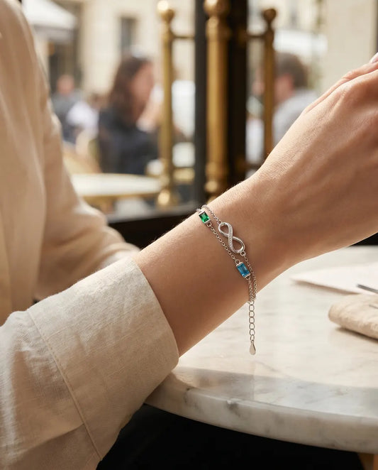 Mujer con la pulsera infinito de dos piedras de nacimiento en una mesa de café