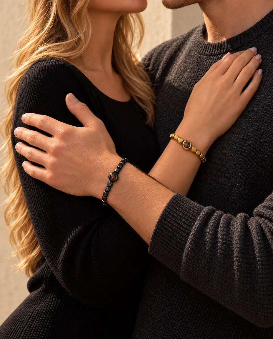 Pareja abrazada: ella lleva la pulsera dorada de cuentas con foto dentro y él, la negra